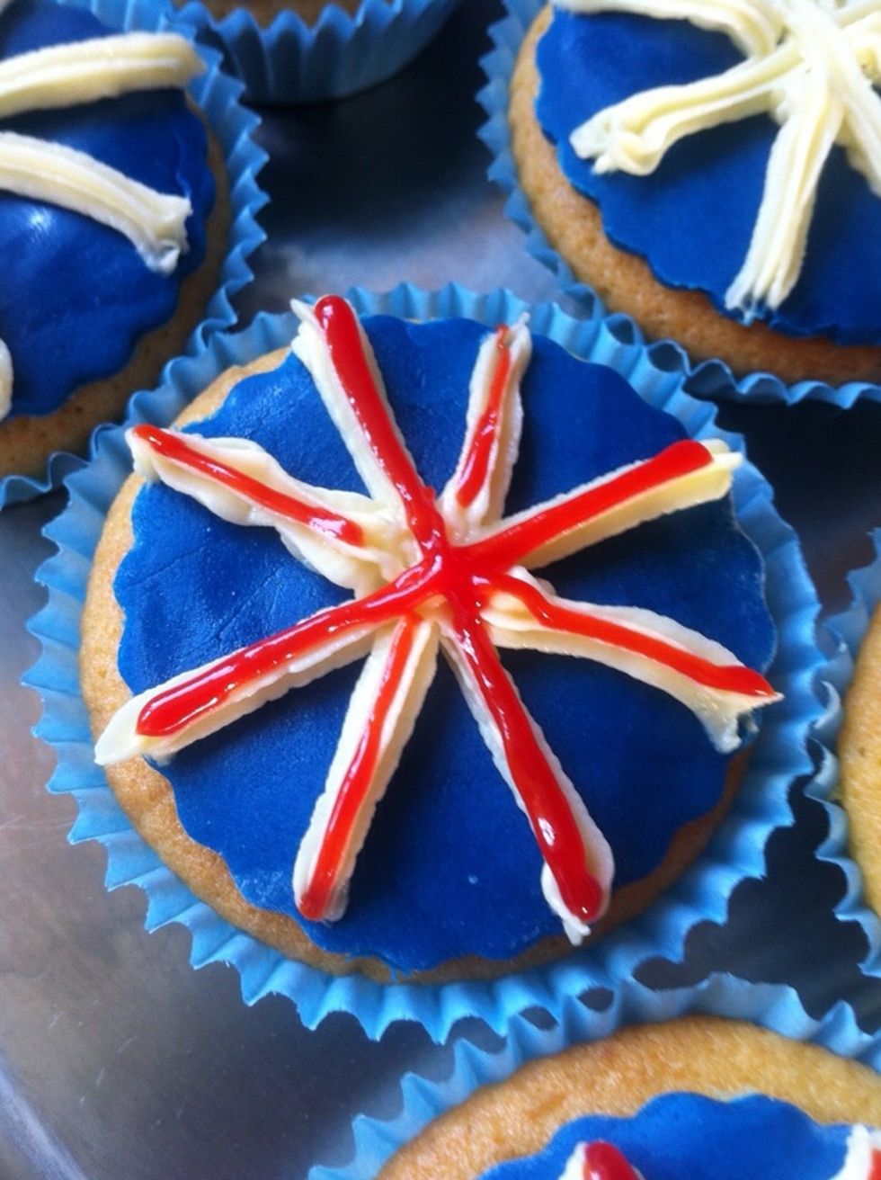 Take your red writing icing (available from supermarkets in the baking aisle) and create the red lines. Go over St George's cross twice to make it thicker. And that's it! Enjoy your jubilee cupcakes!