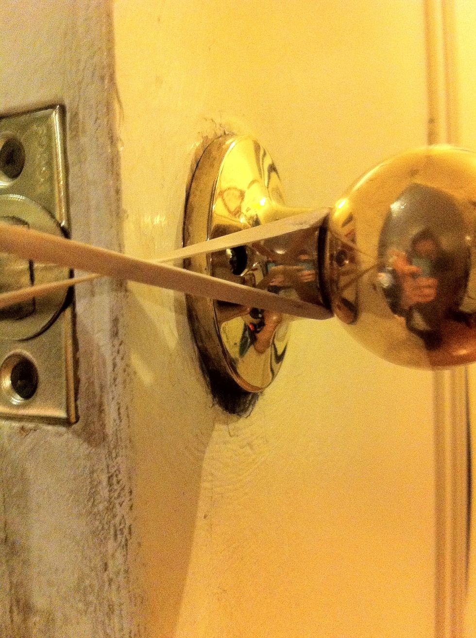 Take your rubber band and wrap around one side of the door knob. Now, pull the elastic and twist!