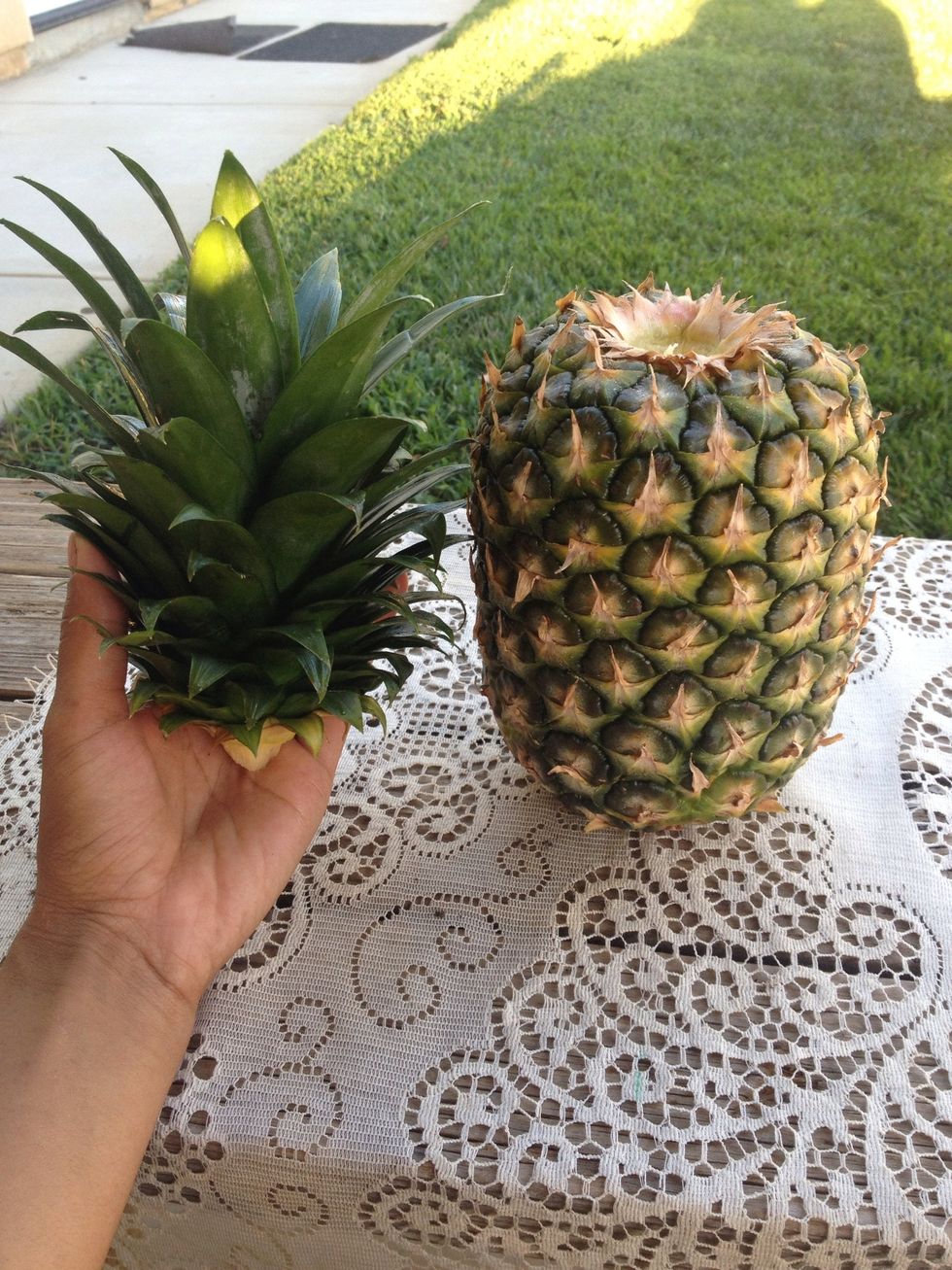 Take your store bought pineapple and simply twist off the top. Hold base of pineapple firm with one hand, with the other grab the top of the fruit where the leaves are and in a twisting motion..pull