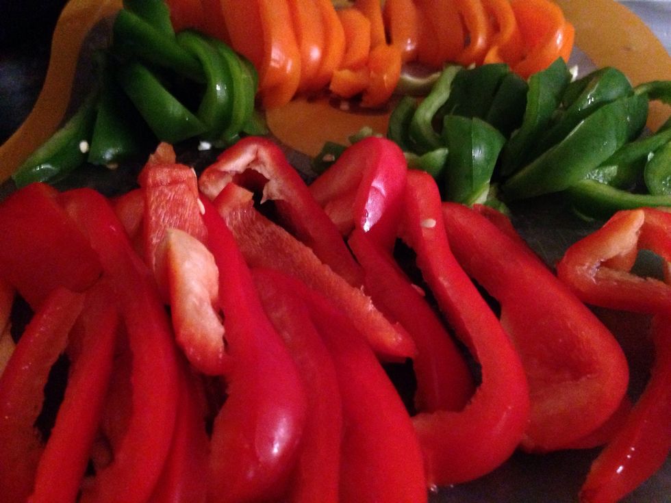 Take your three bell peppers, any colors will do, and cut in half. Remove heart of pepper then proceed to cut into vertical slivers.