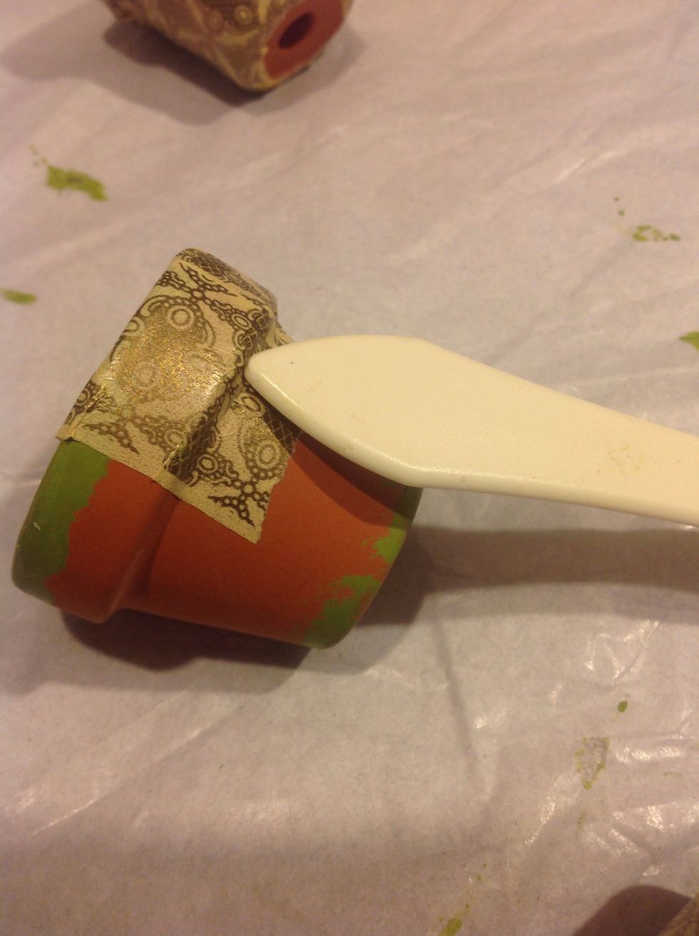 Take your washi tape , I'm using Graphic 45, and start adhering over the top . Use a bone folder to get good contact under the lip of pot.