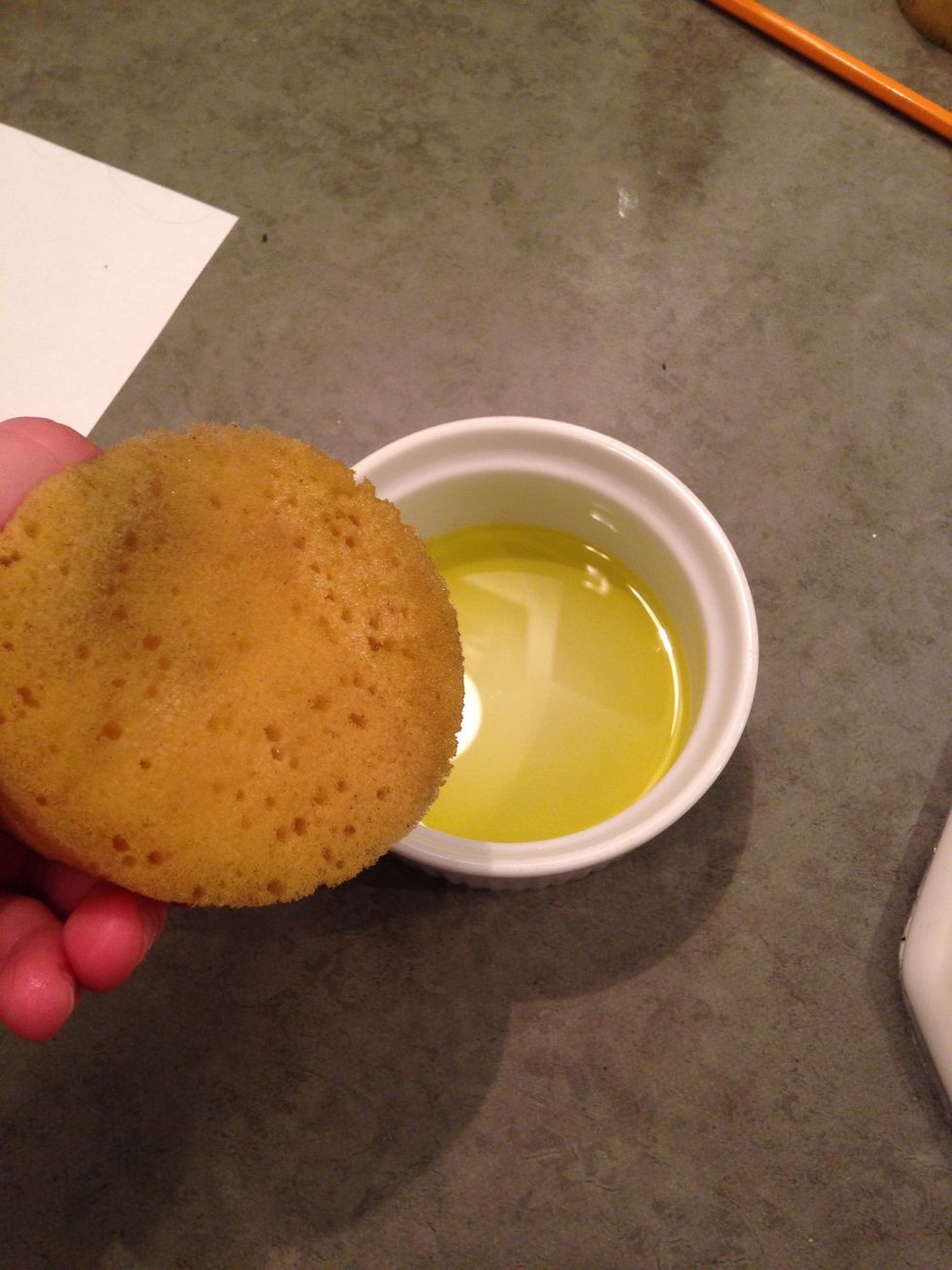 Taking a separate, damp and clean sponge, dip it in olive oil