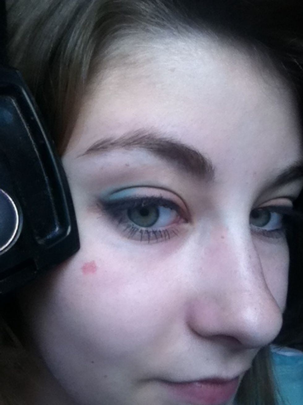 Taking a small angled brush, line your lid with the black eyeshadow, creating a smokey wing at the outer corner.