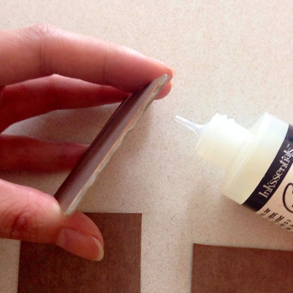 Taking one of the 2" x 2" chipboard, apply glue or glossy accent onto the edge of the chipboard as shown...