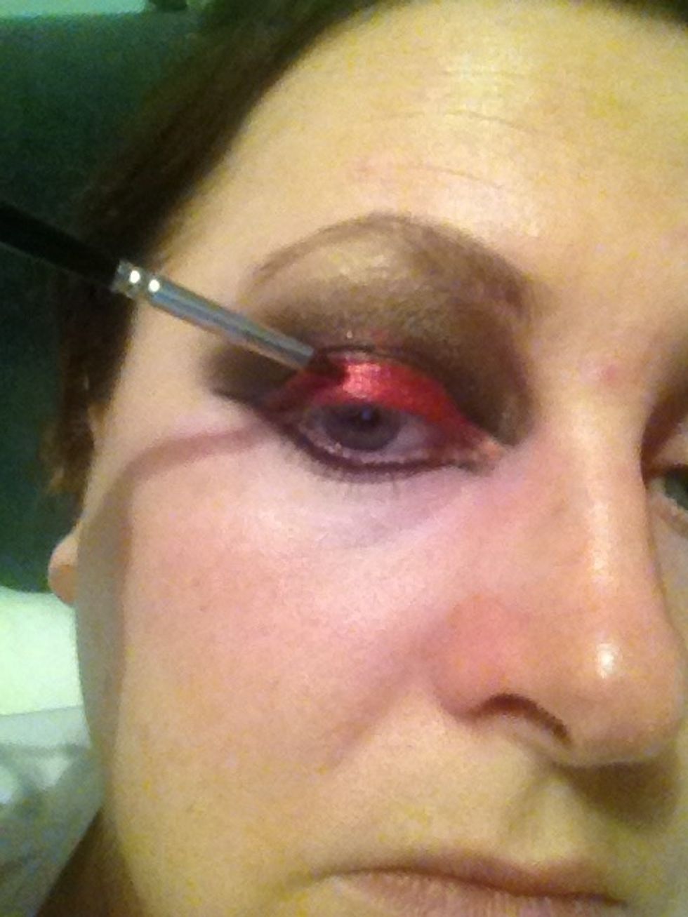 Taking small brush adding the red shadow and pigment along lower lashes and lids
