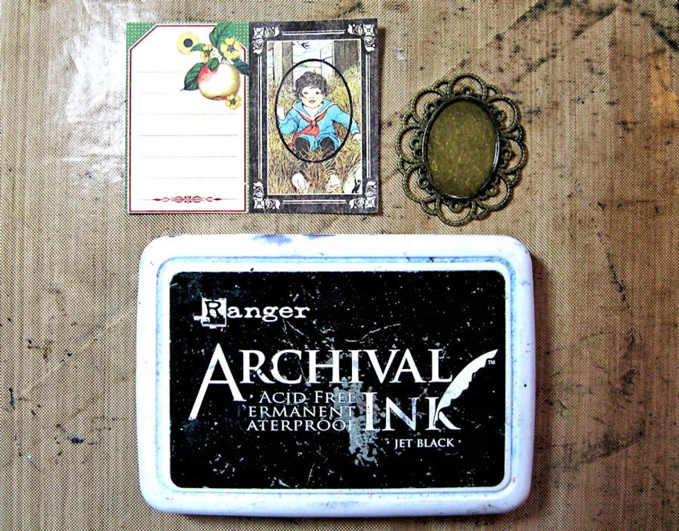 Tap bronze frame with Black Archival ink. While ink is still wet, use it to stamp a frame around the image you want to use inside the frame. Trim the image with scissors. Glue with Glossy Accents.