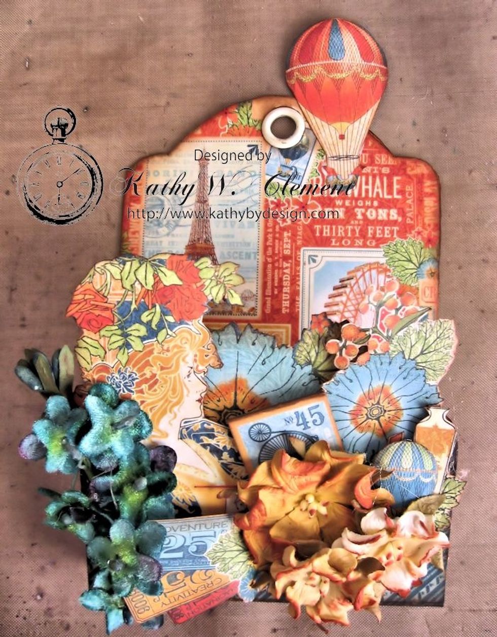 Tap wild roses with ink and add to the pocket base.  Ink the edges of the small World's Fair chipboard and tuck into arrangement.  Add fussy cut hot air balloon to the top of the tag.
