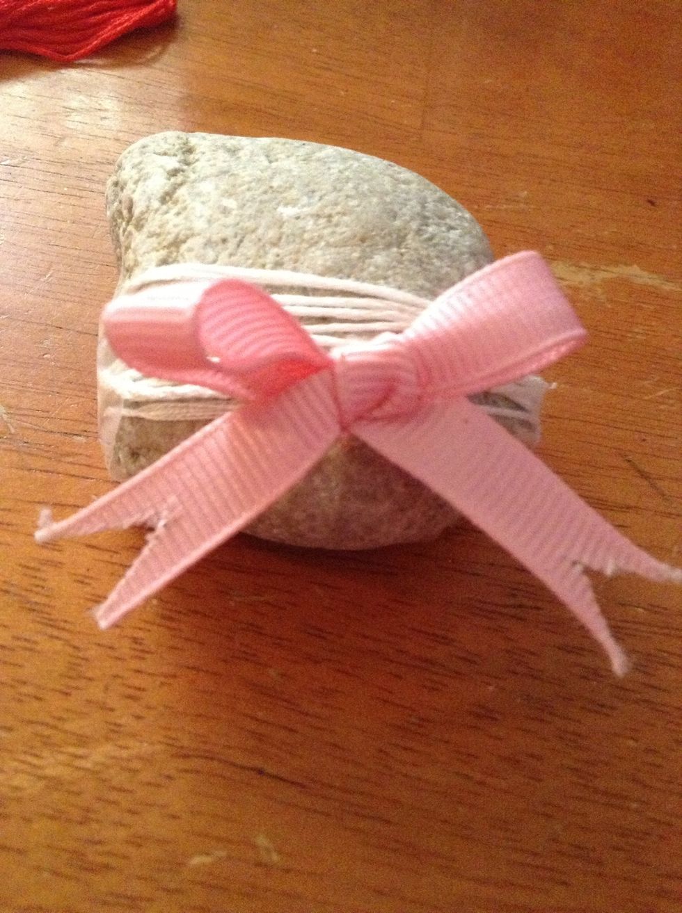 Tape or glue the leftover string to the bottom of the rock. Add an accessory if you like