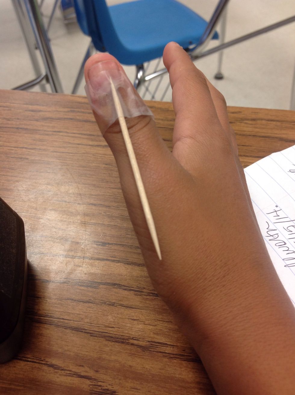 Tape the toothpick to the back of your thumb.