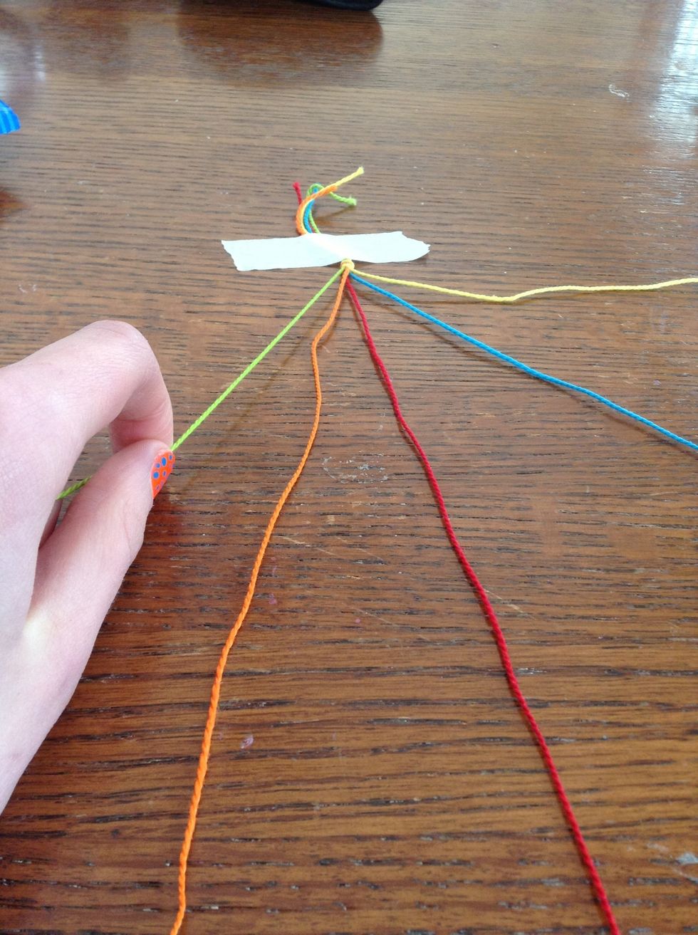 Tape your strings down, and begin the bracelet, by picking up the string farthest to the left.