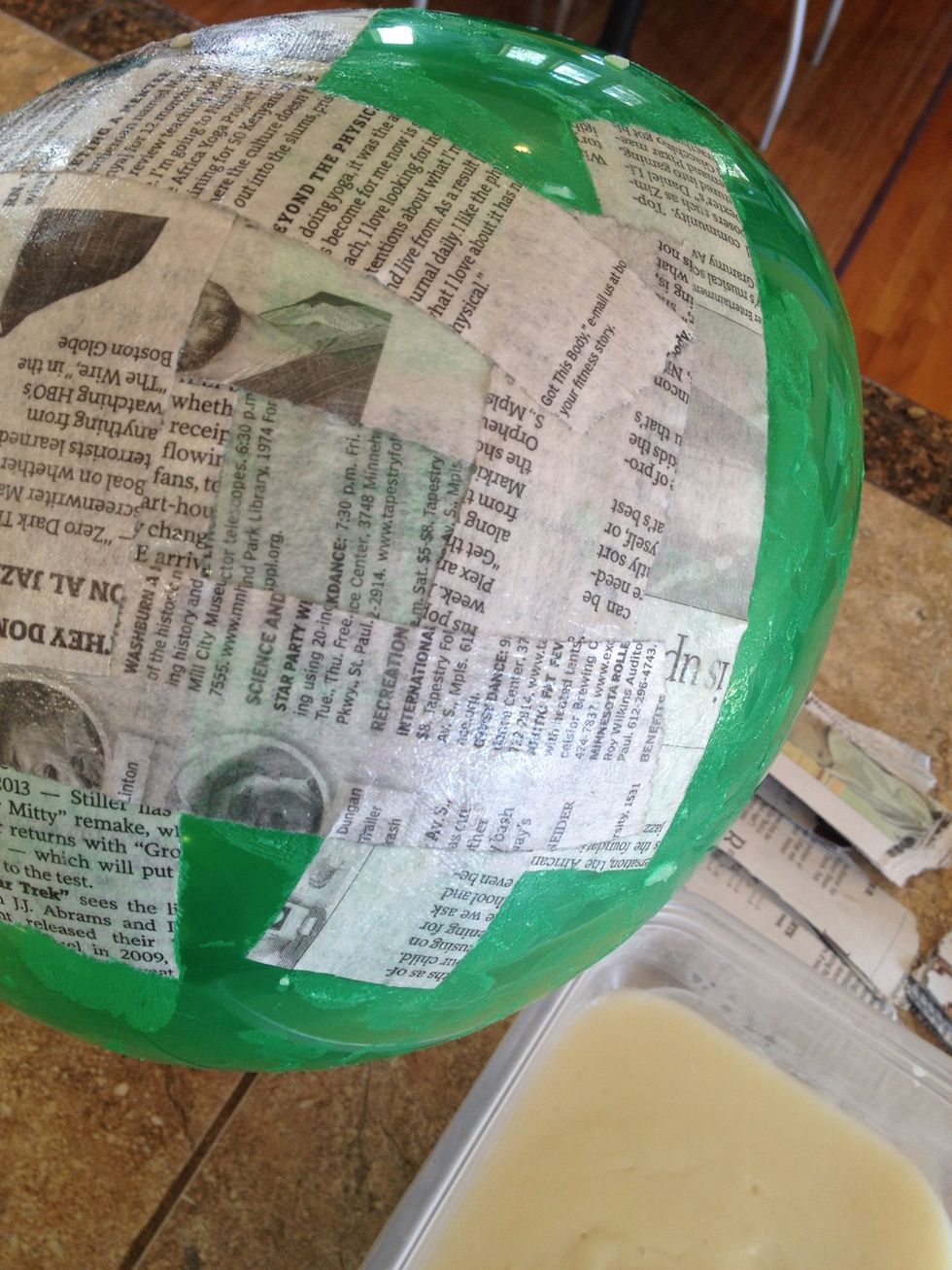 Tear newspaper into strips. Wet strips one at a time with paste and place on balloon.