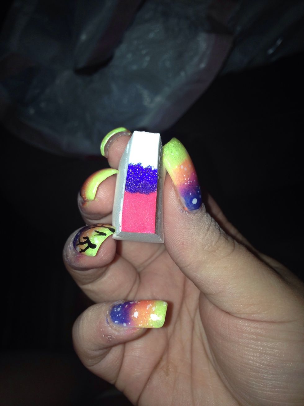 Tearing a cosmetic sponge in half, paint blue, pink, and yellow stripes across the sponge.