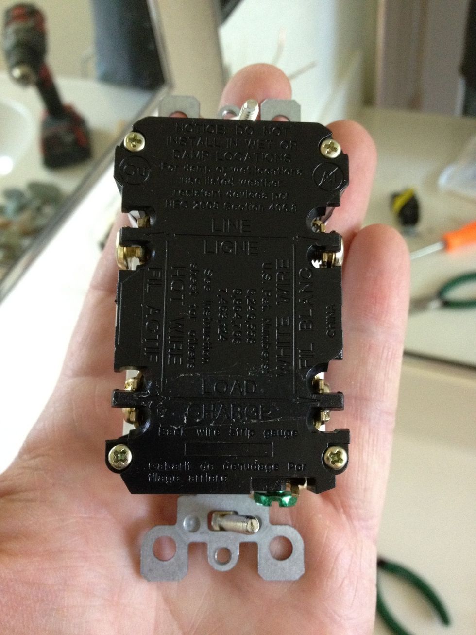 The back of the new outlet. There are 2 connection screws for our wires on each side. A total of 4. How fortuitous that we have 4 wires! The ground wire connects to the green screw at the bottom.