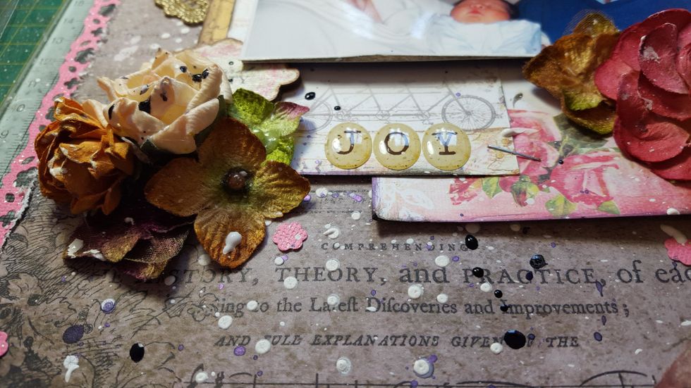 The bottom left corner of the photo slot/glue the Wood Icon between the photo and journal cards. Arrange some flowers below it. Add the title with Epoxy stickers.