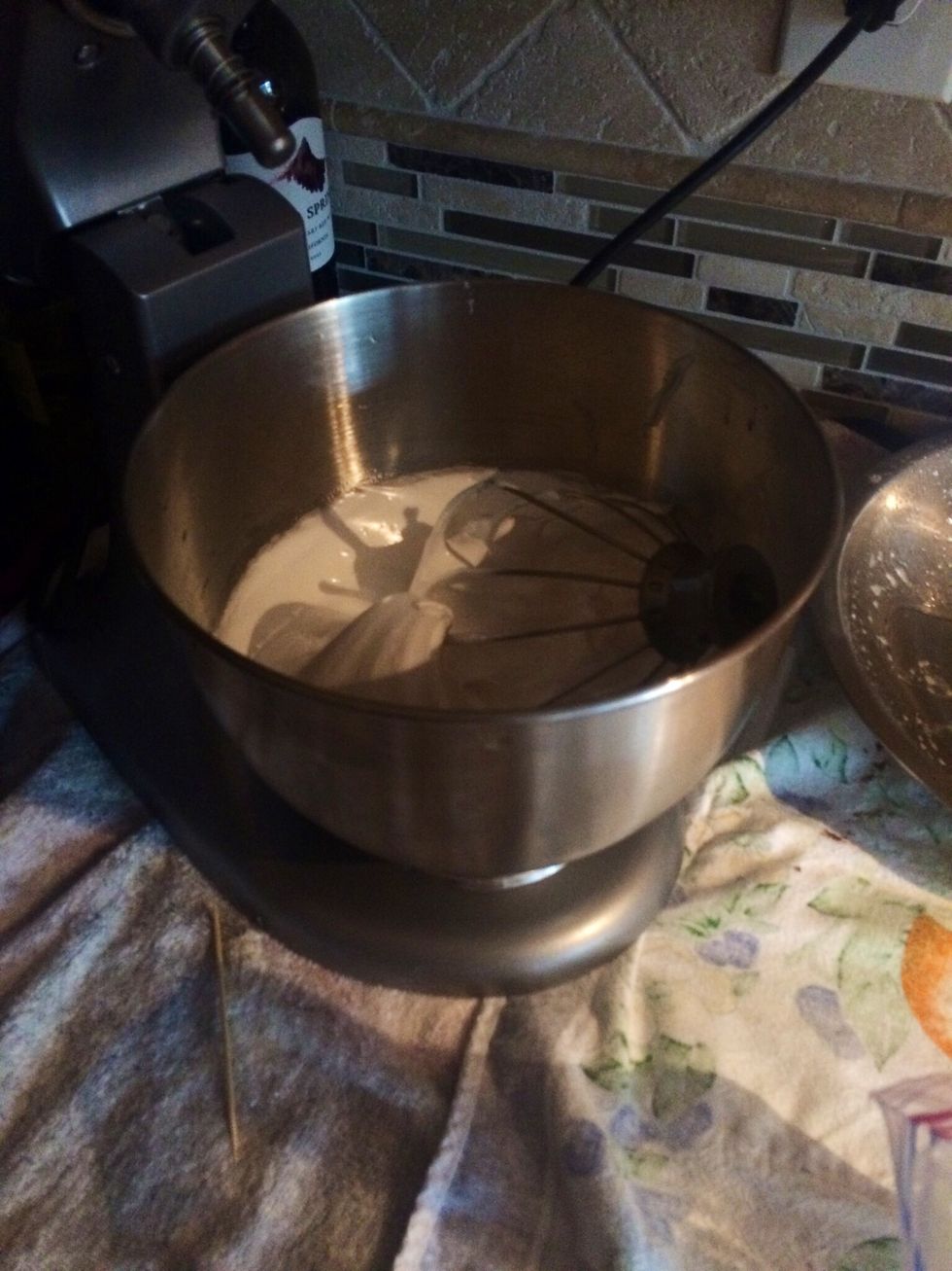 The bowl will be hot so wear gloves, and transfer the mixture into an electric mixer. Beat on low speed using the whisk attachment, and gradually increase the speed, for 5-7 mins. There should be-