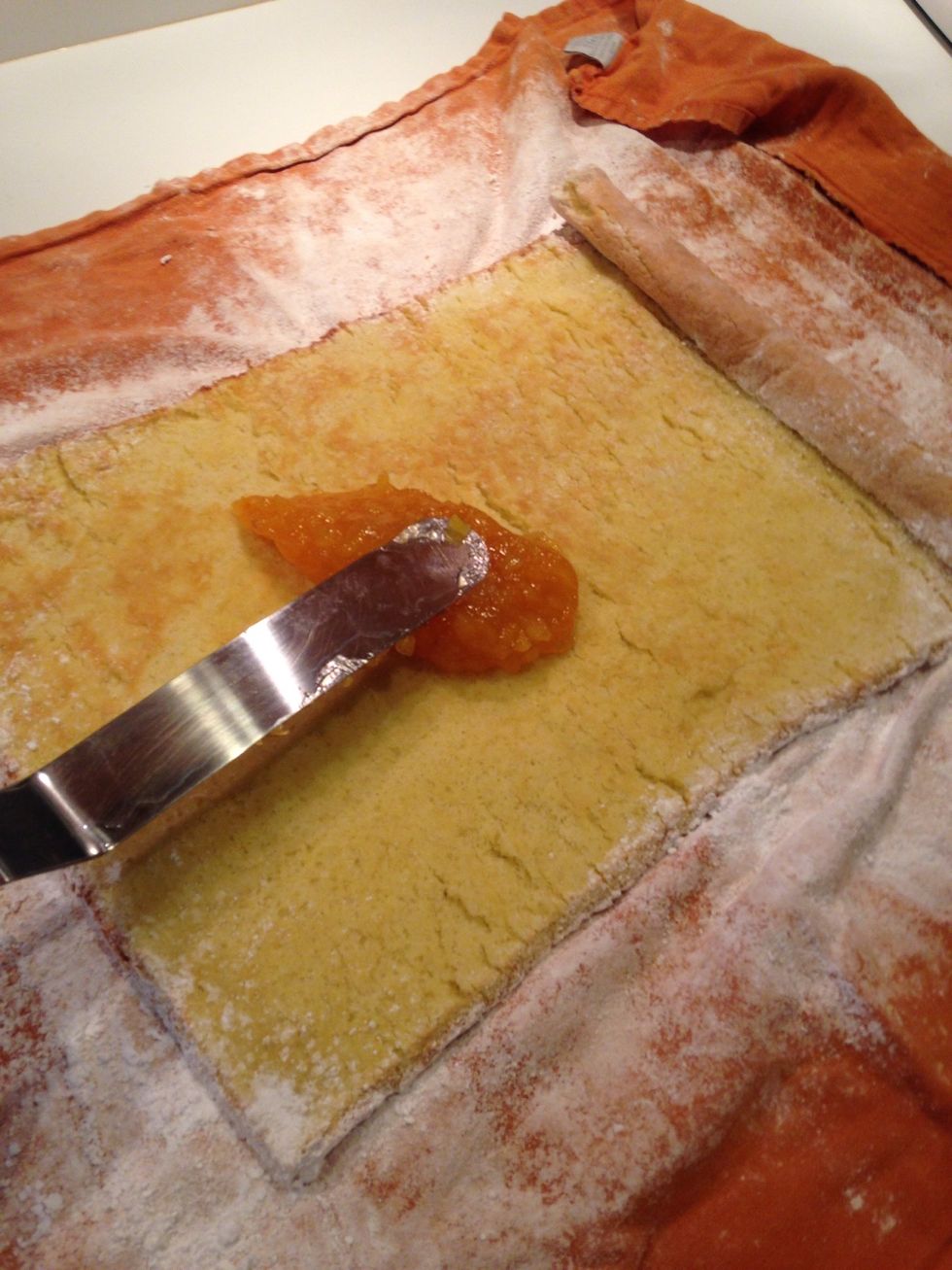 The cake will appear wavy, carefully spread the apricot or fruit filling in an even layer over the cake.