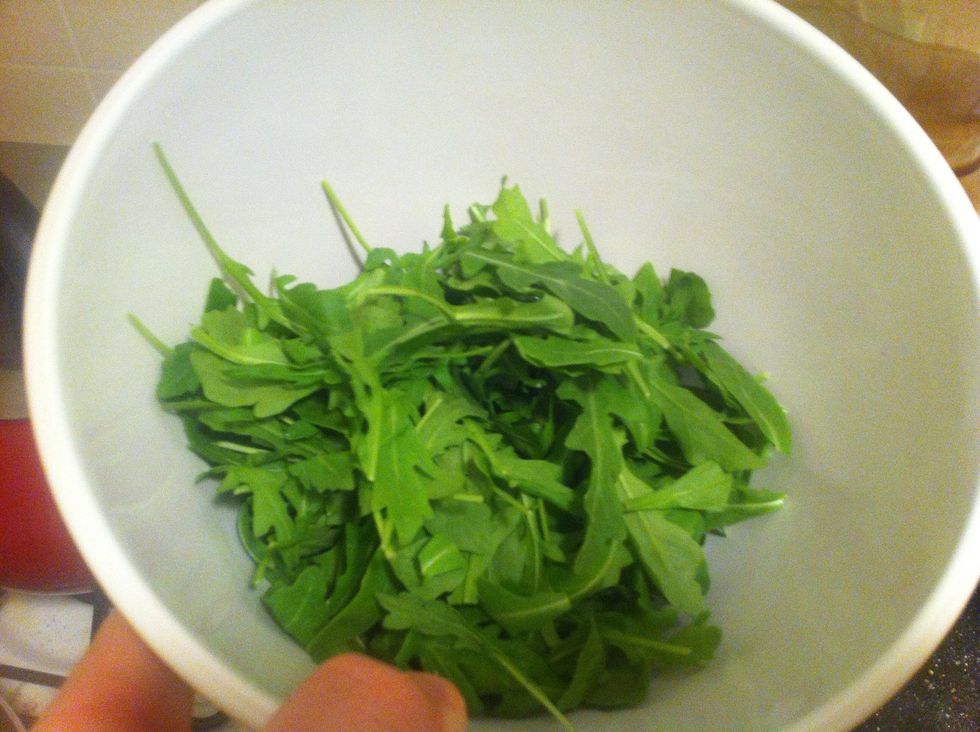 The chicken will take some time, it's worth it!. Meanwhile put a handful of baby arugula in a bowl, I'm not gonna tell you how much to put in, but this salad is going to be amazing, so put a bunch in.