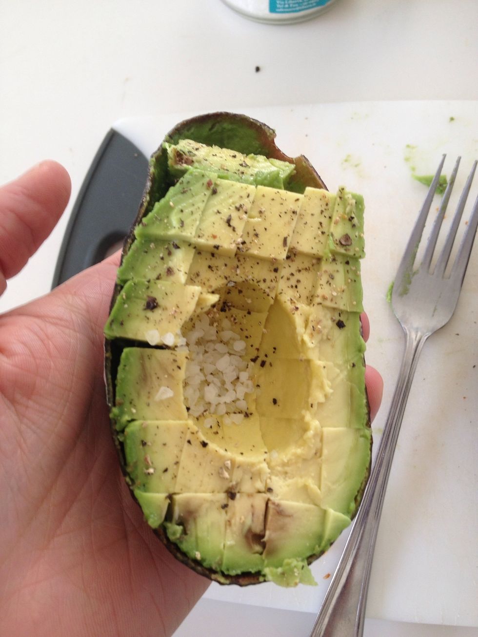 The cubes will become completely detached from the skin. Grip the half avocado with one hand and use a fork to begin gently mashing the chunks.
