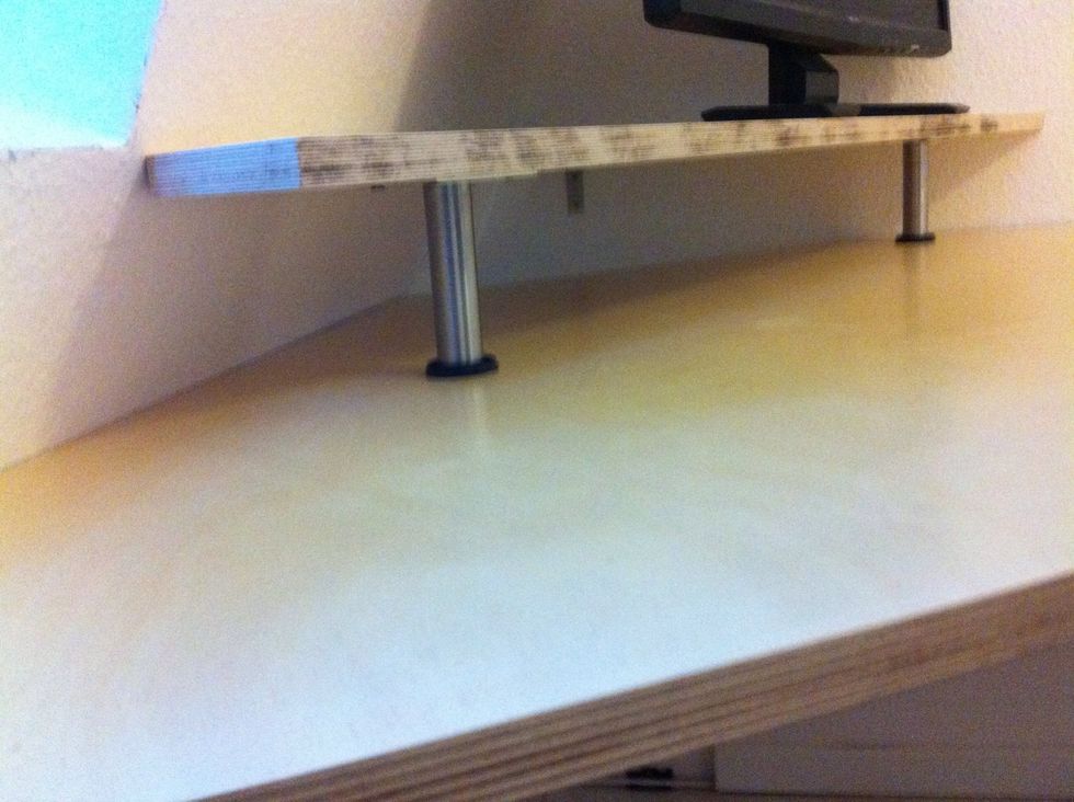 The desk shelf is held by two small legs in the front and one L-bracket mounted on the wall in the back.
