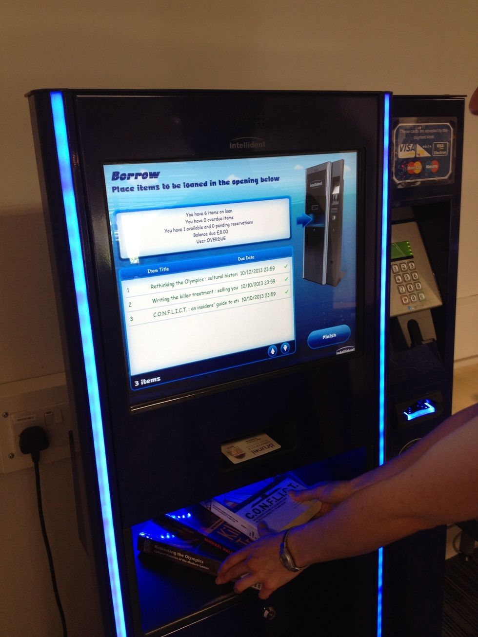 The details for everything you're borrowing should show on screen. Check that everything is listed and has gone green - if you take them out before this then you might set off the alarms.