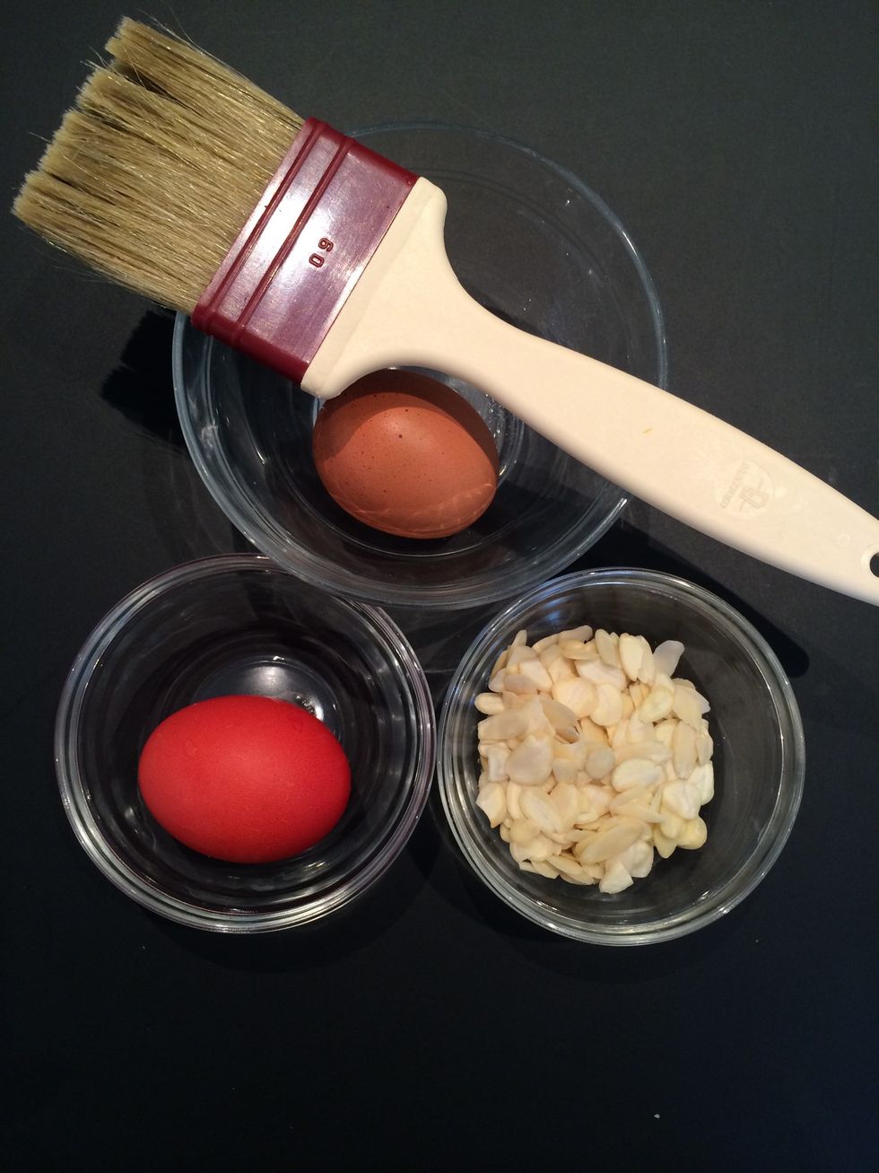 The finishing ingredients: the colored egg, slivered almonds for the top and an egg for glazing.