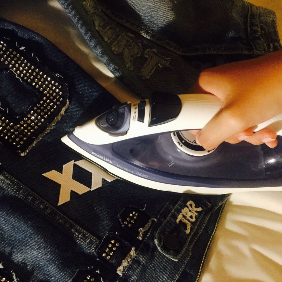 The first method is by heat transfer. Place the iron-on patches on the jacket and have the sticky part facing down.  Then, push iron onto the letters for about 15-20 seconds for each one to stick.
