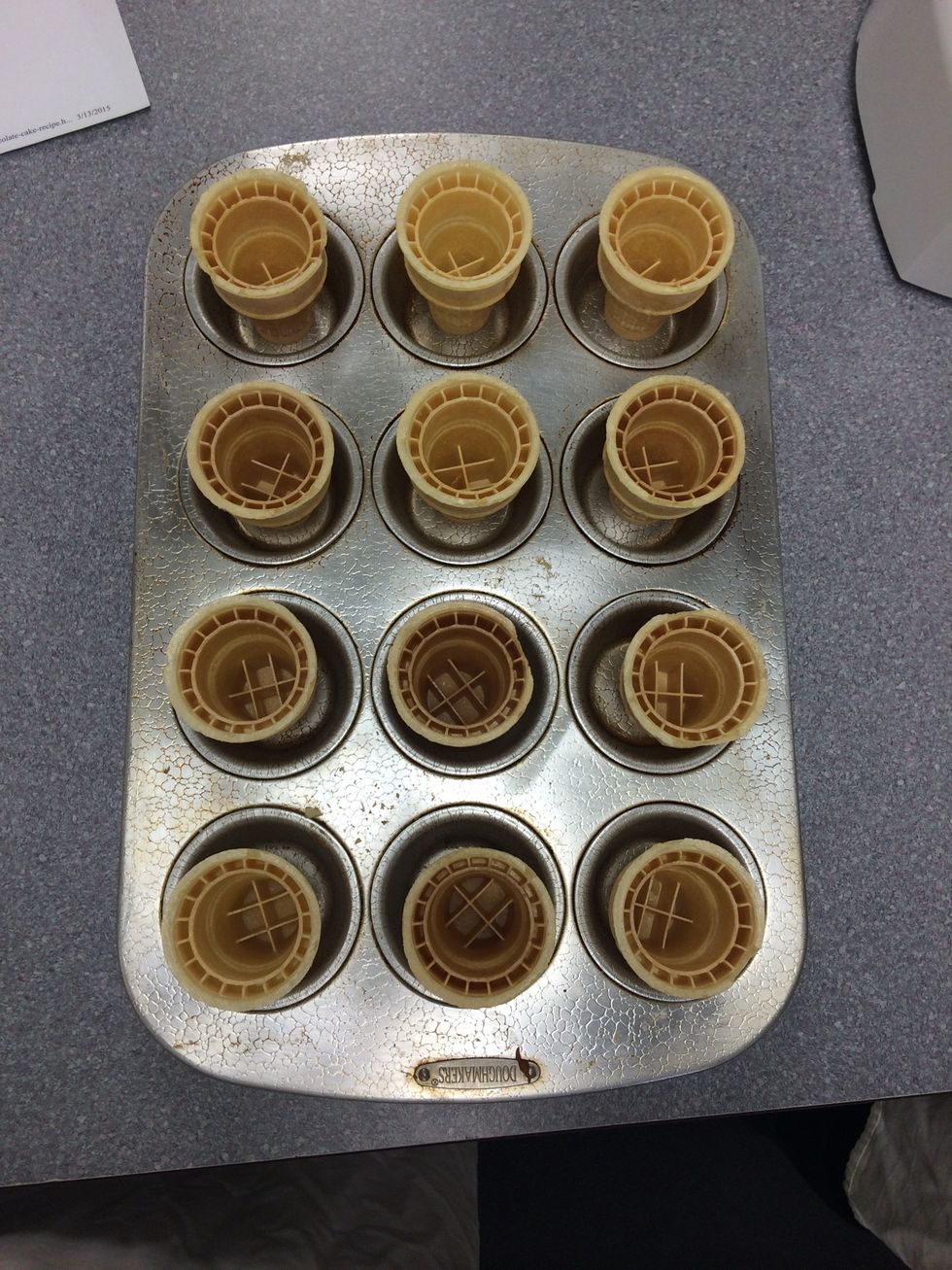 The first step of the chocolate cake cones is to fill a muffin and/or cupcake pan with ice cream cones. Putting it in this pan will help prevent the cones from tipping over during baking.