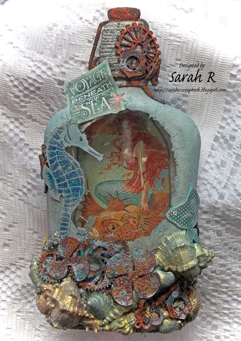 The front of the bottle - includes Creative Embellishments Seahorse & clusters of gears, washers/nuts, key & propellers at the top and bottom. A Tropical Fish chipboard curves around the right side.