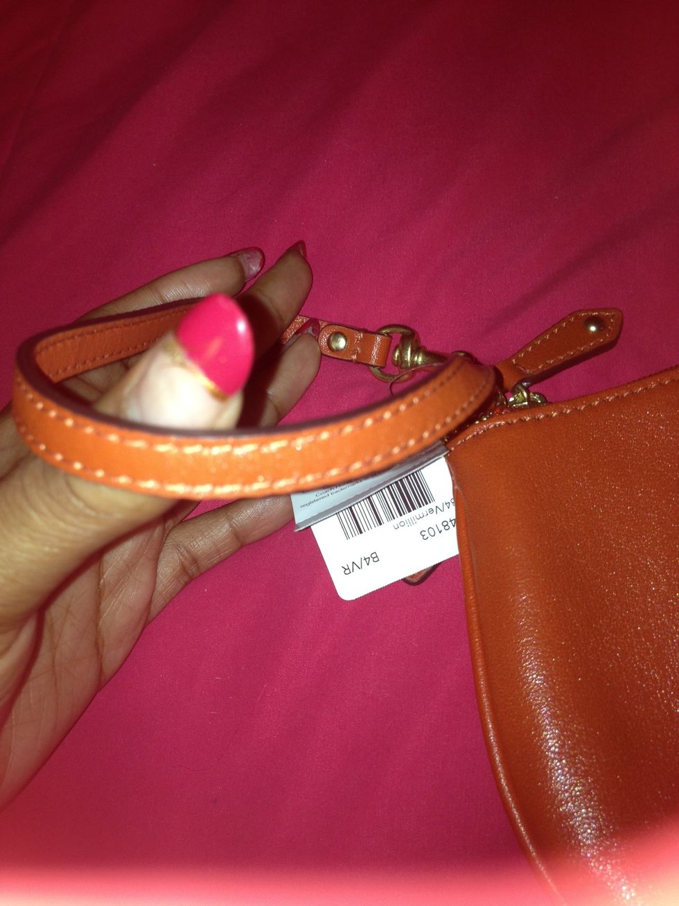 The handle of the wristlet,noticing the stitching, it's a little hard to tell but it's the same dark orange color as the item itself.