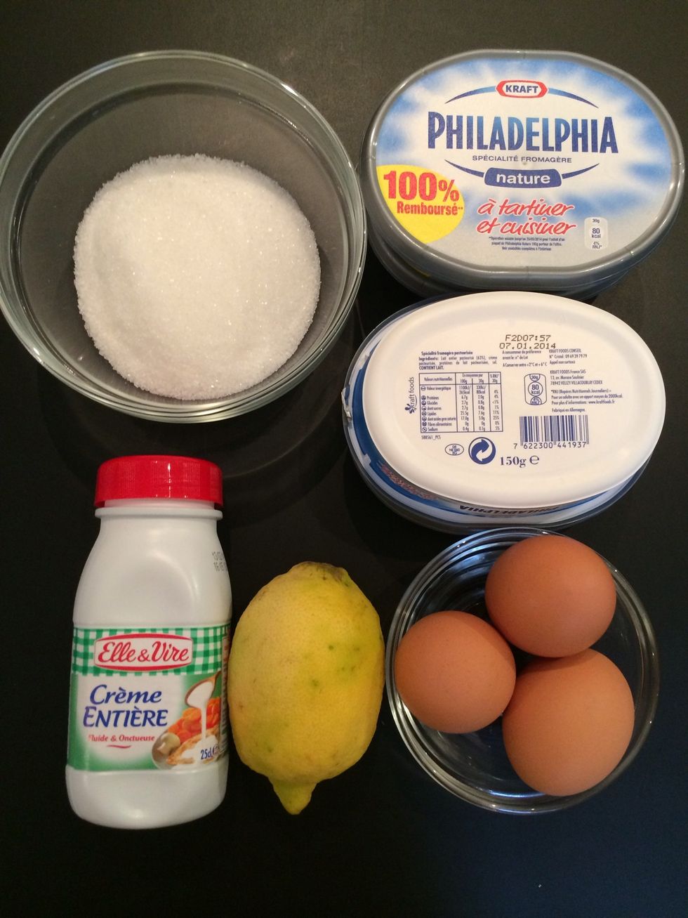 The ingredients: In a mixer put the cheese & sugar beat.. Add eggs 1 by 1 alternating with the flour sifted, (not to make lumps) the cream, lemon zest and lemon juice. (Forgot the 2 yolks in z photo)