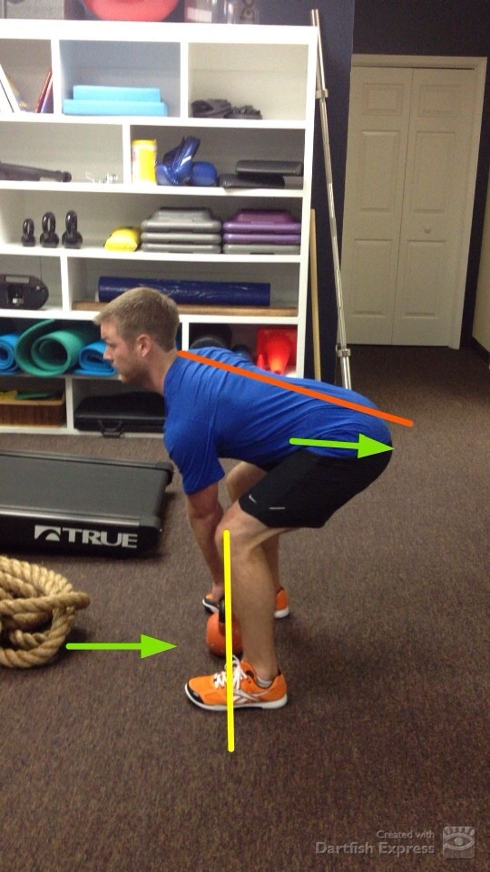 The kettlebell (KB) should be placed approximately mid foot in stance. Address the KB by hinging hips backward and bending the knees while maintaining a vertical shin & straight back.