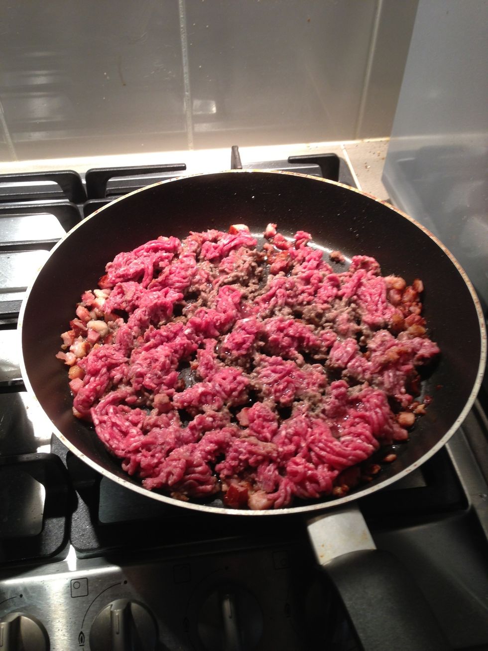 The minced beef will start to brown up, you can start turning the mince over, just flip it over with a wooden spoon or similar cooking utensil