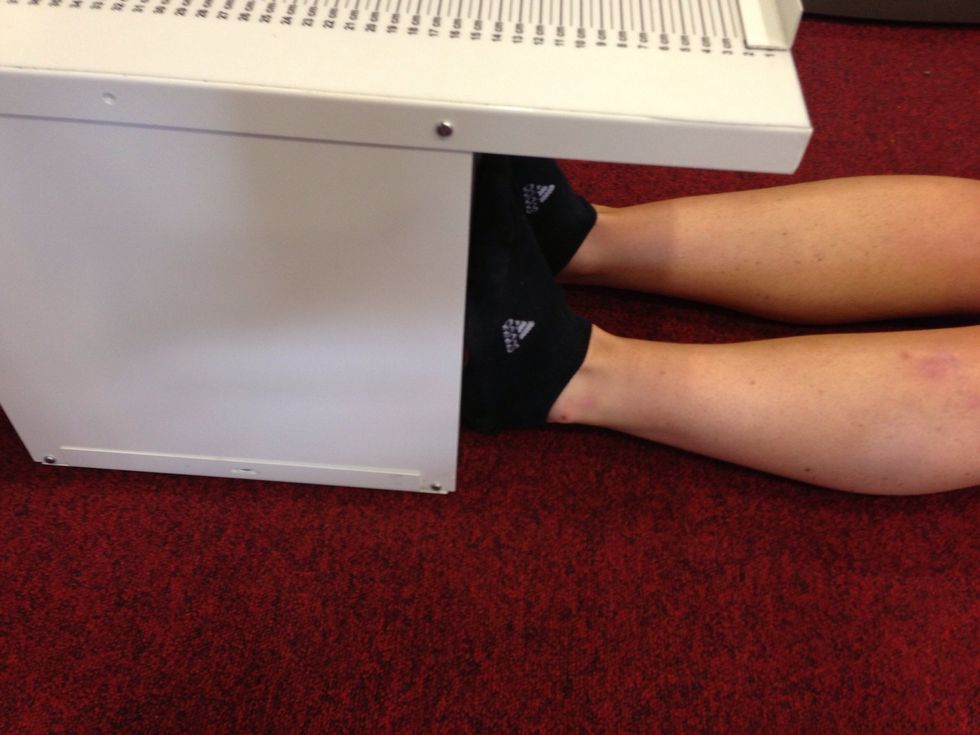 The participant should sit on the floor, legs straight and feet (no shoes) flat against the box.