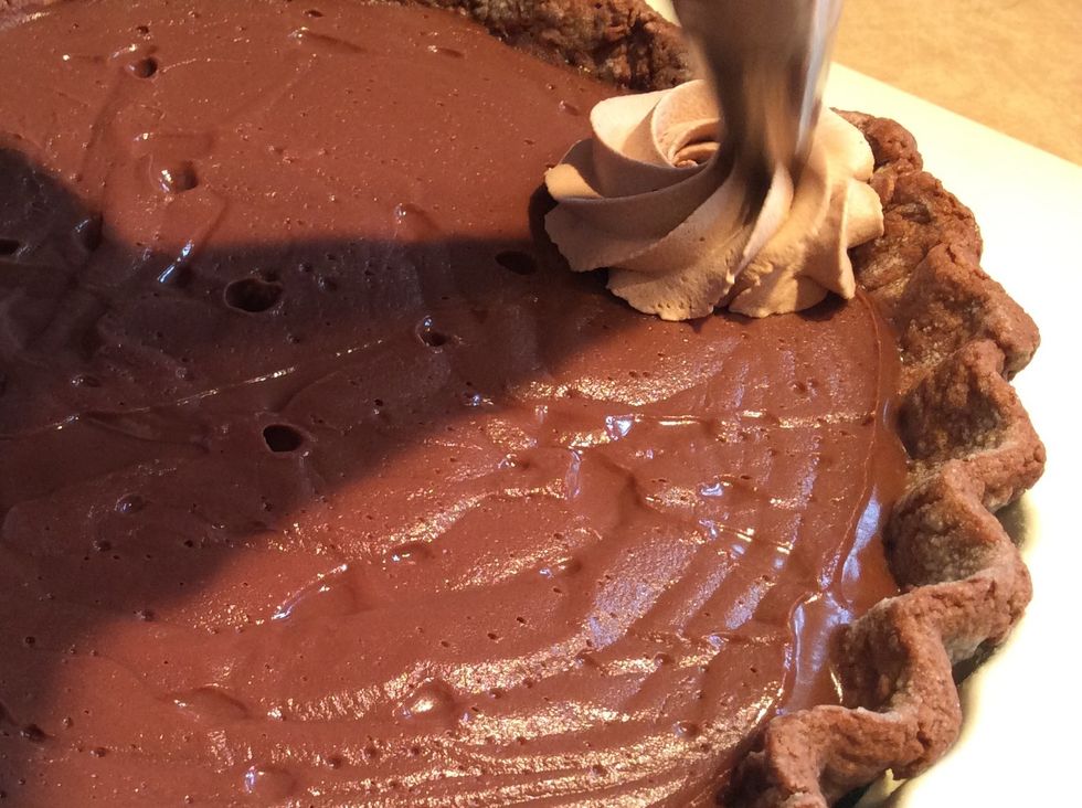 The pastry bag is filled with the chocolate whipped cream. Pipe in circular motions to cover the entire top of the pie with the chocolate whipped cream.