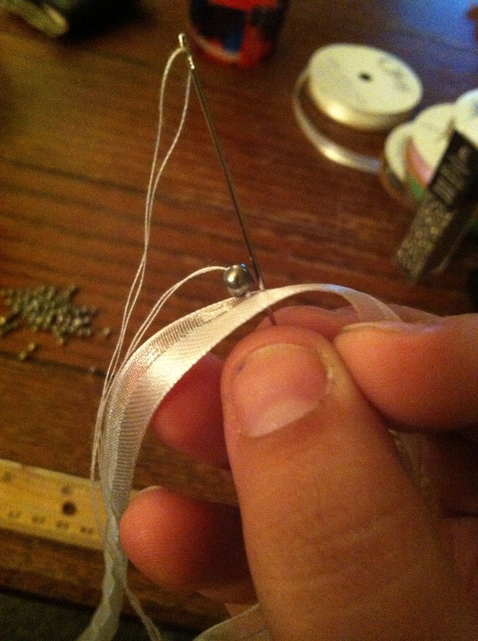 The picture shows what'll happen if you do pull it through. If you we're smarter than me, fold the ribbon over the bead and into the needle.
