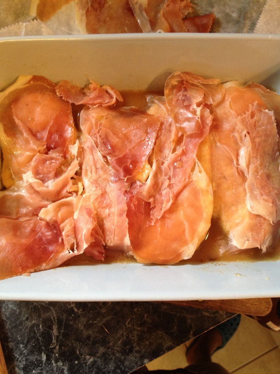 The prosciutto is over the chicken.