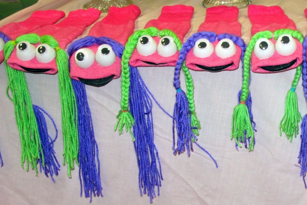The puppets are dyed tube socks.  The eyes are ping pong balls cut in half with eyes from Michaels.  The mouth is black poster board.  The hair is braided yarn and tacked on with thread.