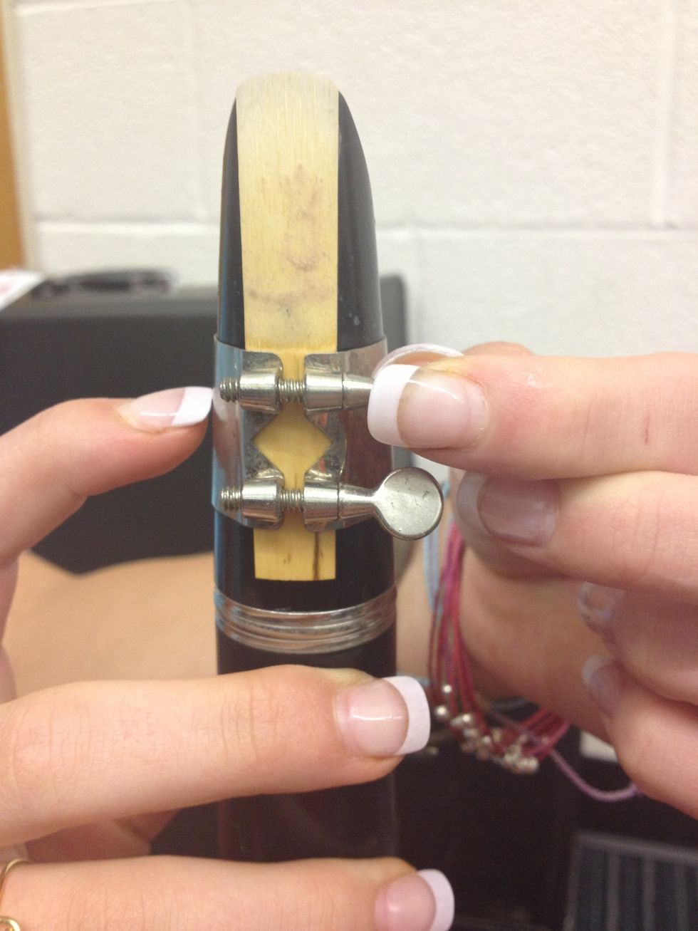 The ring-like object with two knobs is the ligature and the thin strip of wood is the reed.