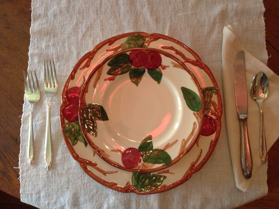 The salad plate goes on top of the dinner plate. We are serving salad ahead of the main course in the "western fashion".