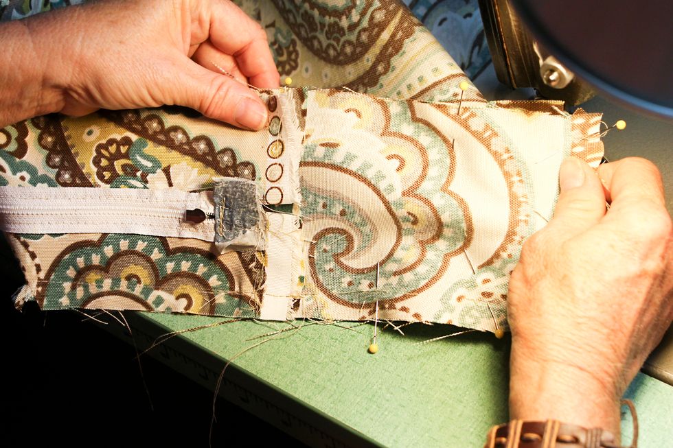 The side that has the zipper continuing past the corner should have the  fold over to hide the zipper tab.