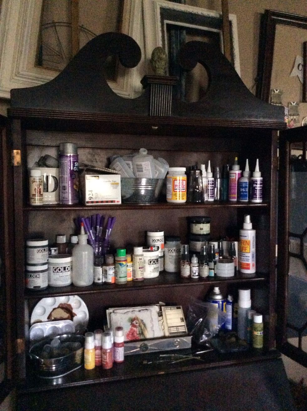 The top half of an old secretary desk houses paints, adhesives and such.