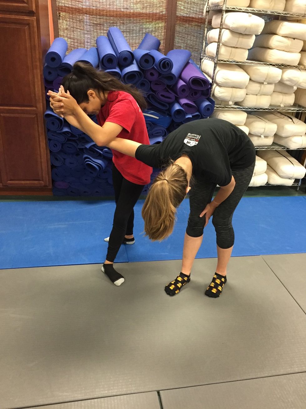 The victim bends down and spins to disable the assailants arm into an arm bar.