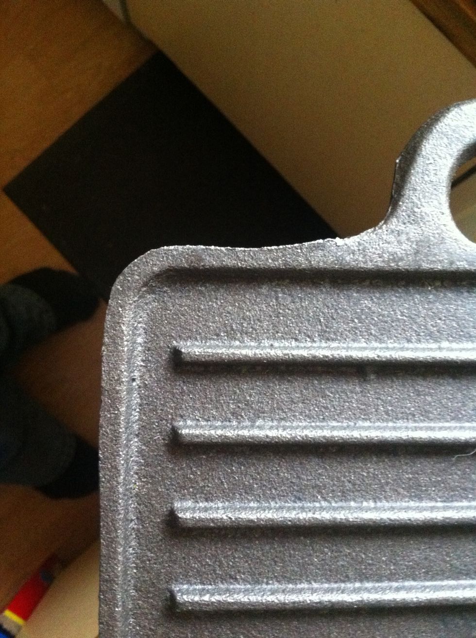 The wax needs to be removed with a scourer  in hot water and washing up liquid before seasoning can take place. (the metal scourers are the best) You will end up with a black/gray metal like this.