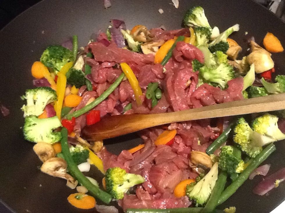 Then add the 700g beef strips and again stir around until the strips lose the red colour