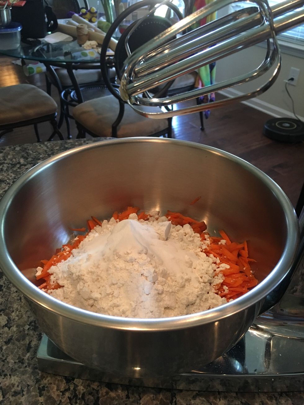 Then, add the baking soda to the mixing bowl with grated carrots, all-purpose flour, baking powder, and baking soda.