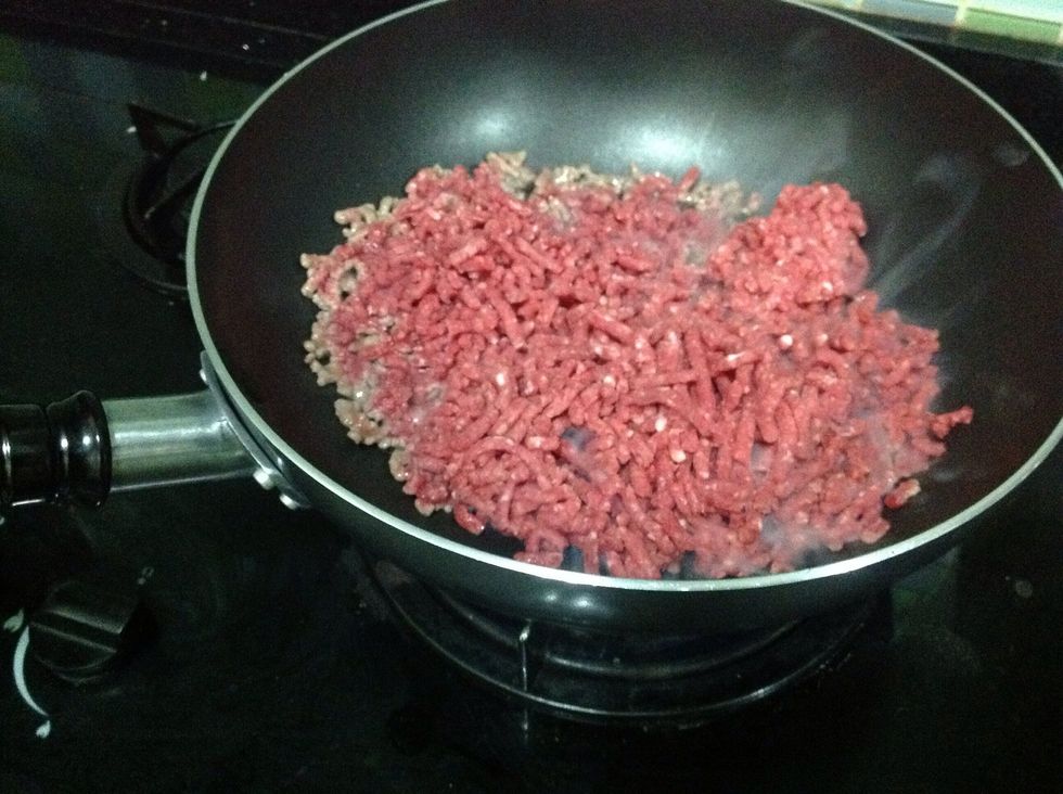 Then add the ground beef and immediately break them up, mixing it.