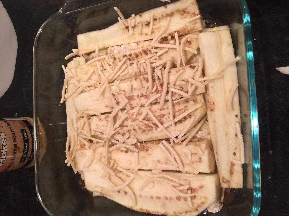 Then add your eggplant slices. Sprinkle vegan mozzarella on top of the eggplant.