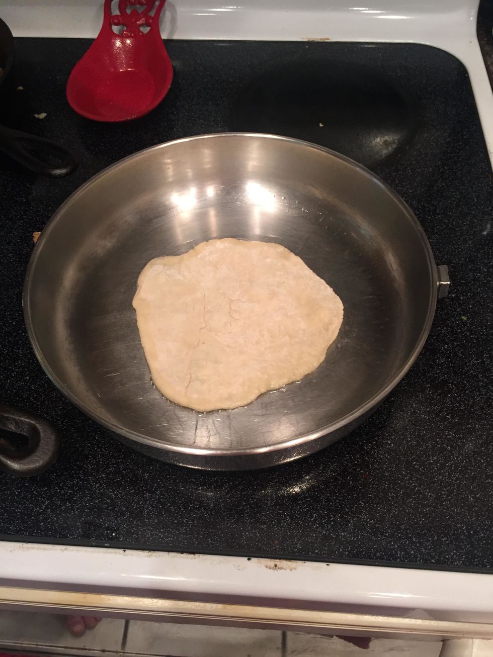 then begin cooking the tortillas on the heated pan one at a time. once the oil begins bubbling, flip the tortilla to the opposite side.