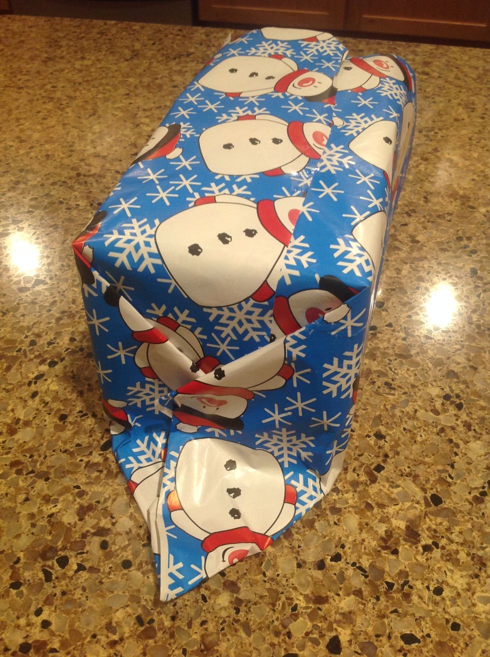 Then, completely crease the end down so that if forms a triangle at the base of the gift.