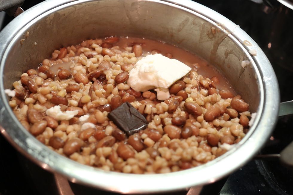 Then drop one cube of Knorrox and a half of Solid Vegetable Oil and take a cup and take two spoons of Beef Onion Soup and add warm water then stir until it's not lumpy then pour it in